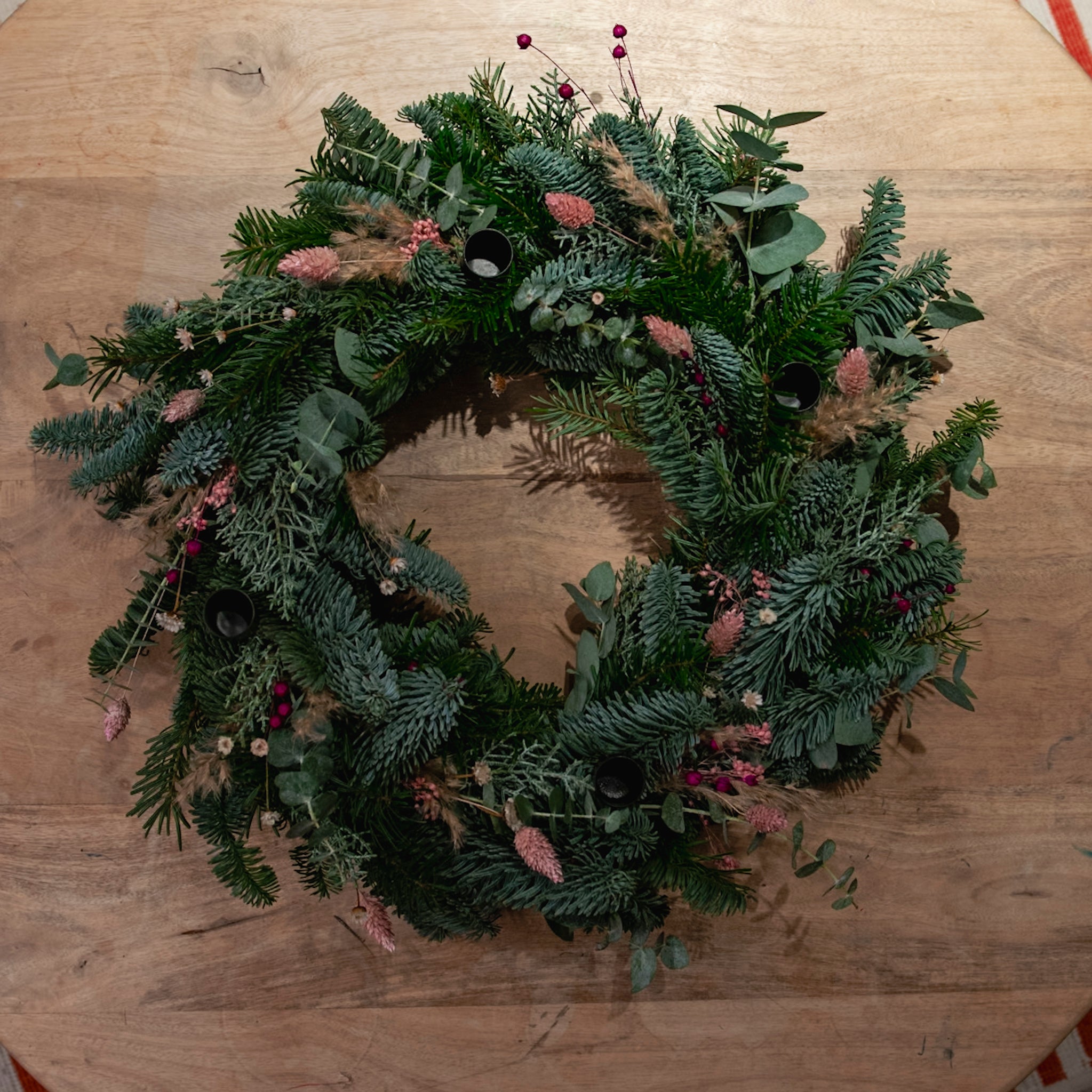 StraightCurls-Adventskranz-Workshop FFB Emmering: grüner Kranz mit Eukalyptus, rosa-rot, auf Holz.