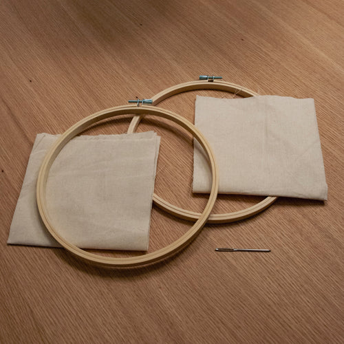 Straightcurls 20 cm Punch-Needle-Stickrahmen-Set mit zwei Rahmen, Baumwollstoff und einer Nadel auf einer Holzunterlage.
