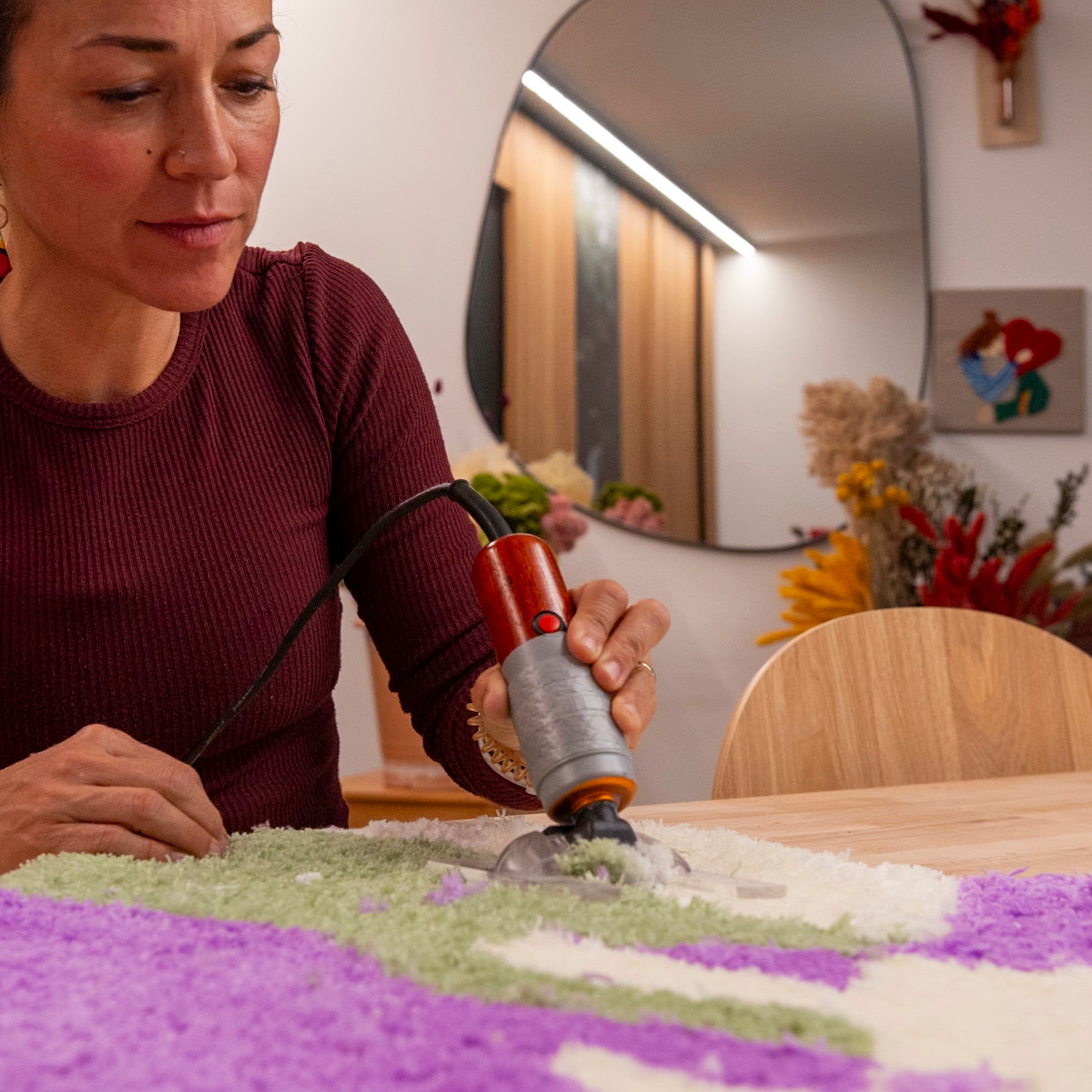 Im Tufting-Workshop FFB Emmering von StraightCurls entstehen aus grünem, weißem und lila Garn einzigartige Tufting-Kunstwerke auf einem Holztisch.
