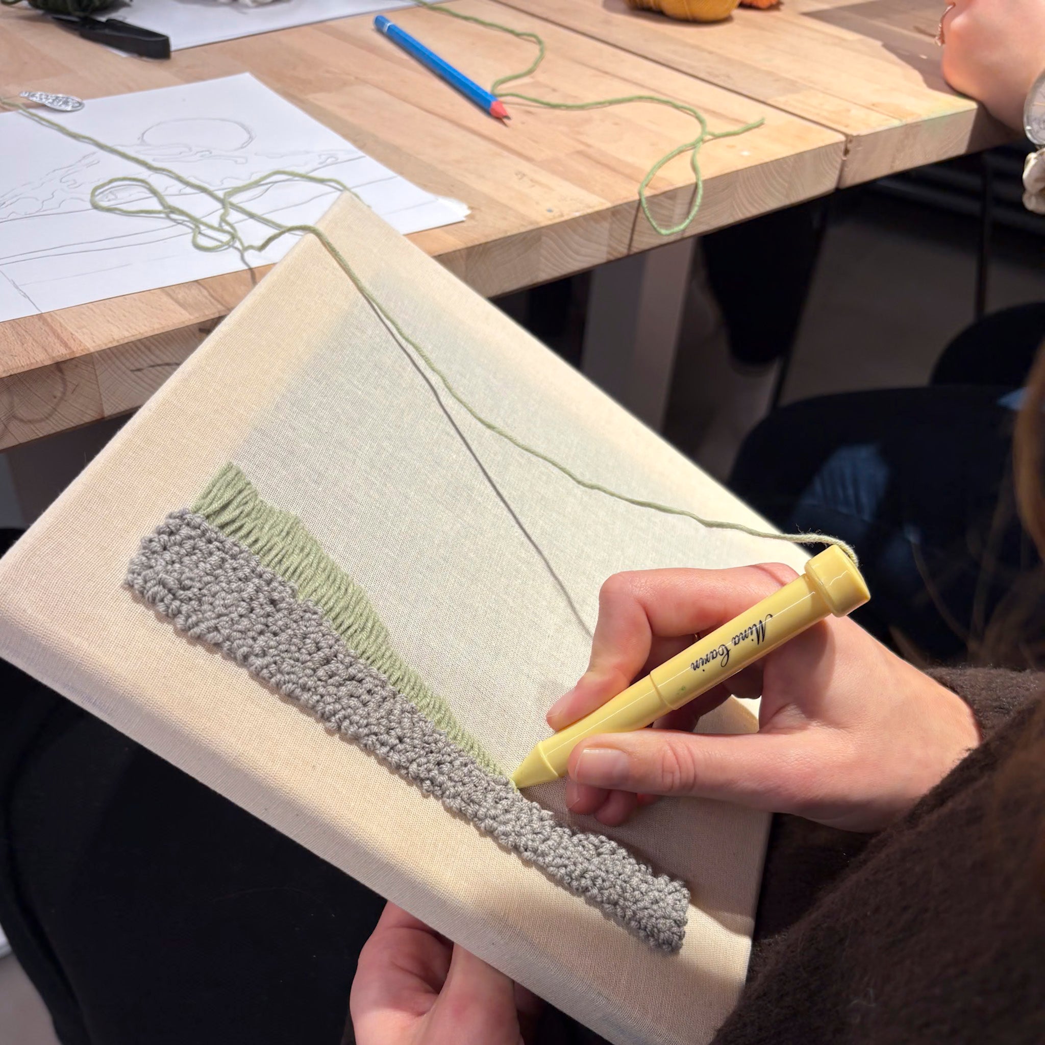 StraightCurls veranstaltet einen Punch Needle Workshop FFB Emmering, bei dem mit grünem Garn auf Leinwand strukturierte Stickereien entstehen.