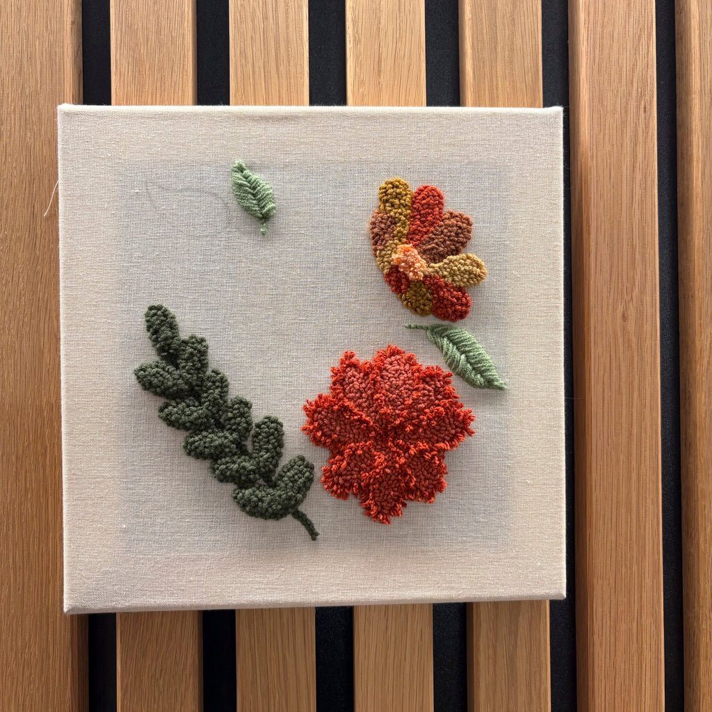 Punch Needle Workshop FFB Emmering von StraightCurls bietet eine strukturierte Blumenstickerei auf einem Hintergrund aus Holzlatten.
