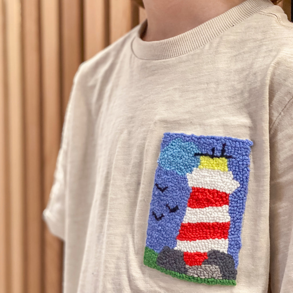 Hochwertiger Leuchtturm-Punch Needle Patch auf einem Kinder-Shirt aus dem StraightCurls Workshop in Emmering/FFB.