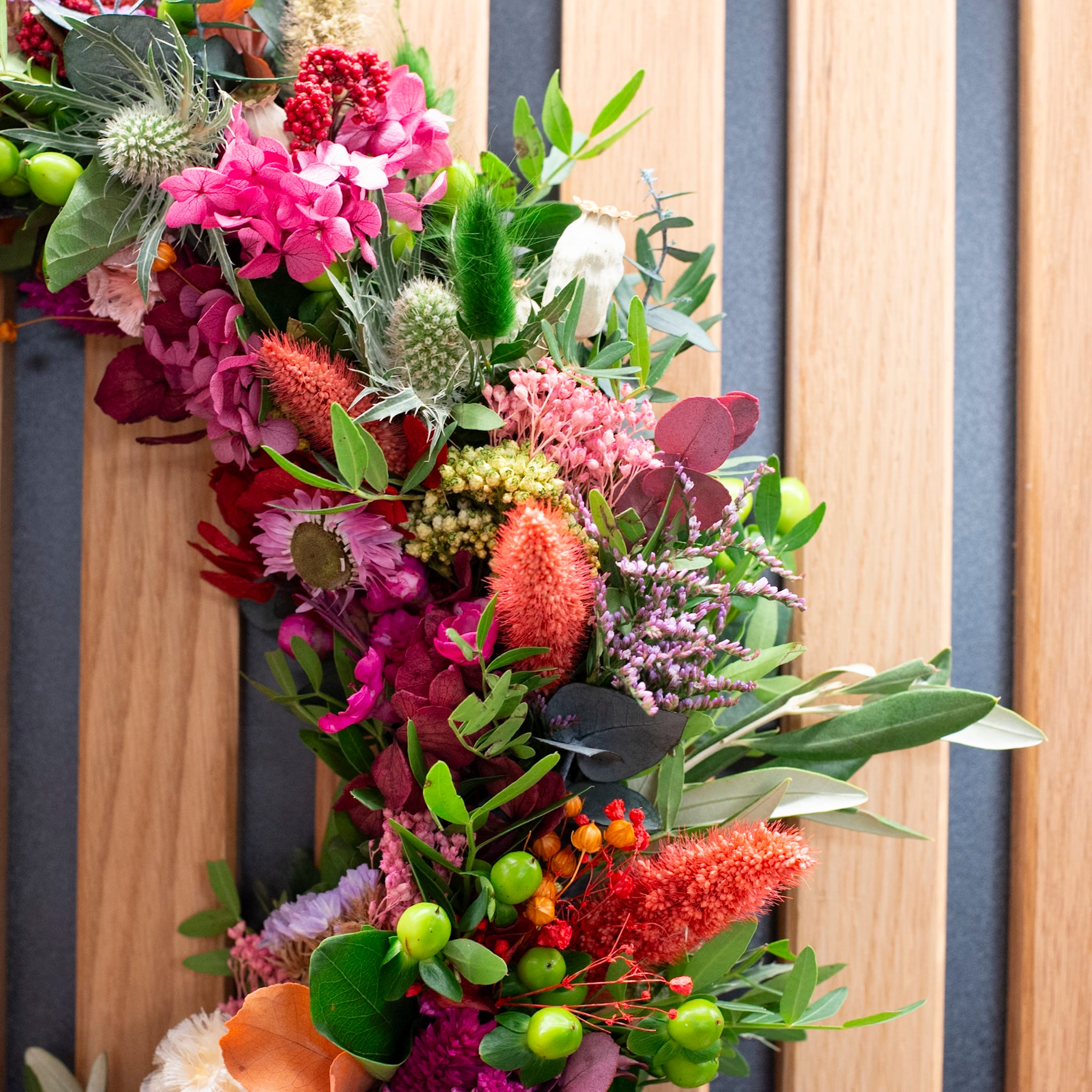 Nahaufnahme der floralen Texturen und bunten Beeren eines langlebigen StraightCurls Blumenkranzes.