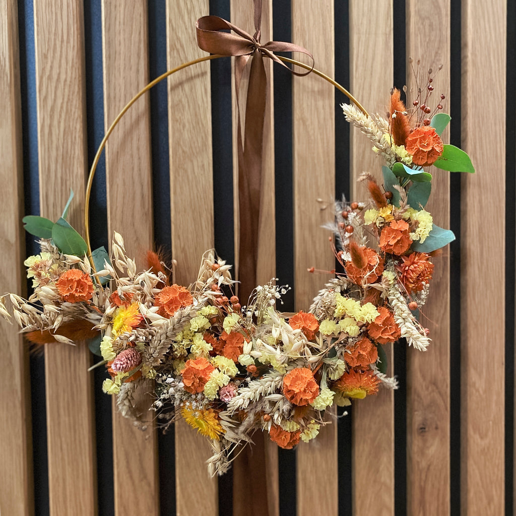 Eleganter Blumenkranz auf Goldring mit orangefarbenen Blüten und brauner Satinschleife von StraightCurls.