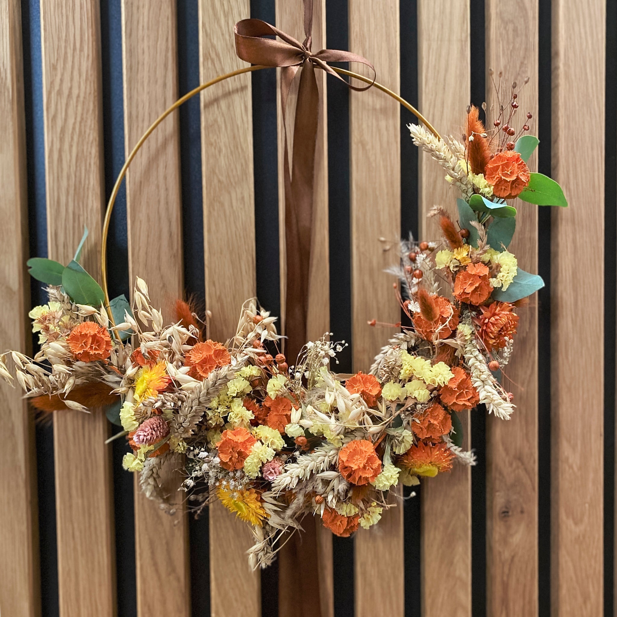 Eleganter Blumenkranz auf Goldring mit orangefarbenen Blüten und brauner Satinschleife von StraightCurls.