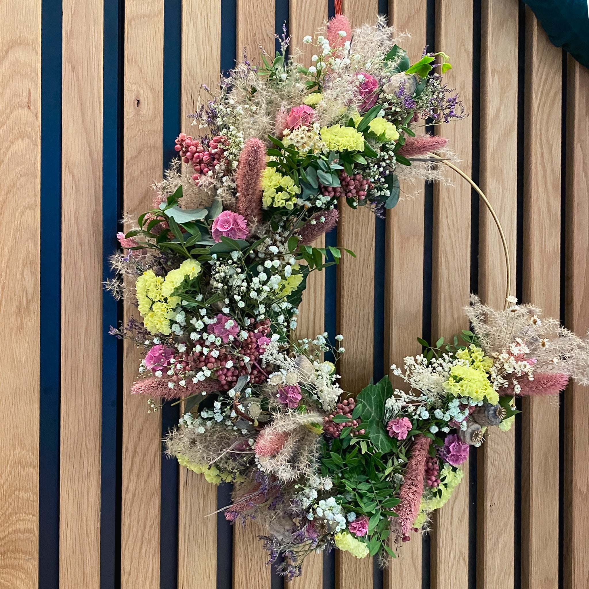 Fluffiger Blumenkranz in Pastelltönen auf einem goldenen Ring von StraightCurls.