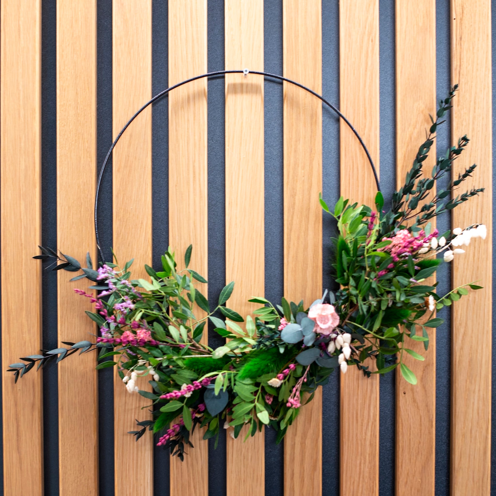 Zart gebundener grüner Blumenkranz mit dezenten floralen Highlights von StraightCurls.