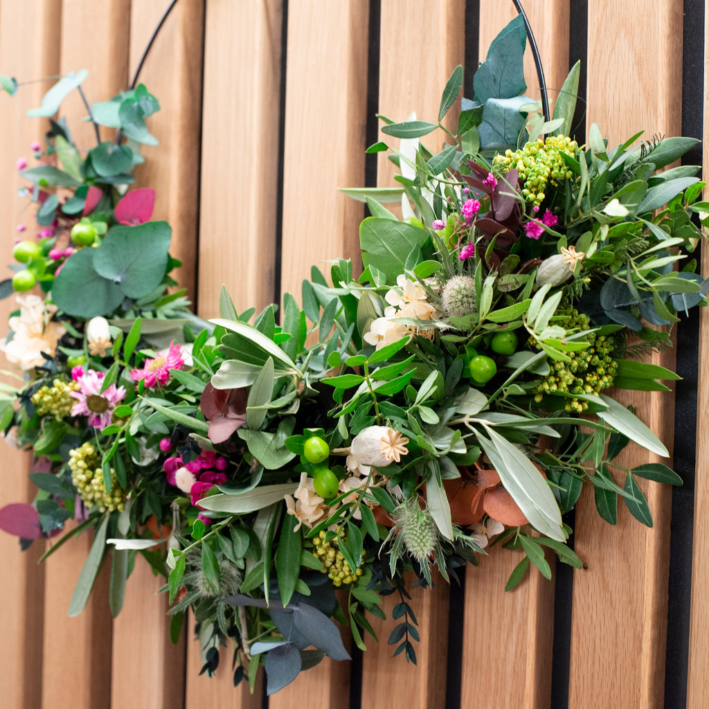 Detailansicht eines langlebigen Kranzes aus frischen Olivenzweigen und zarten Blüten von StraightCurls.