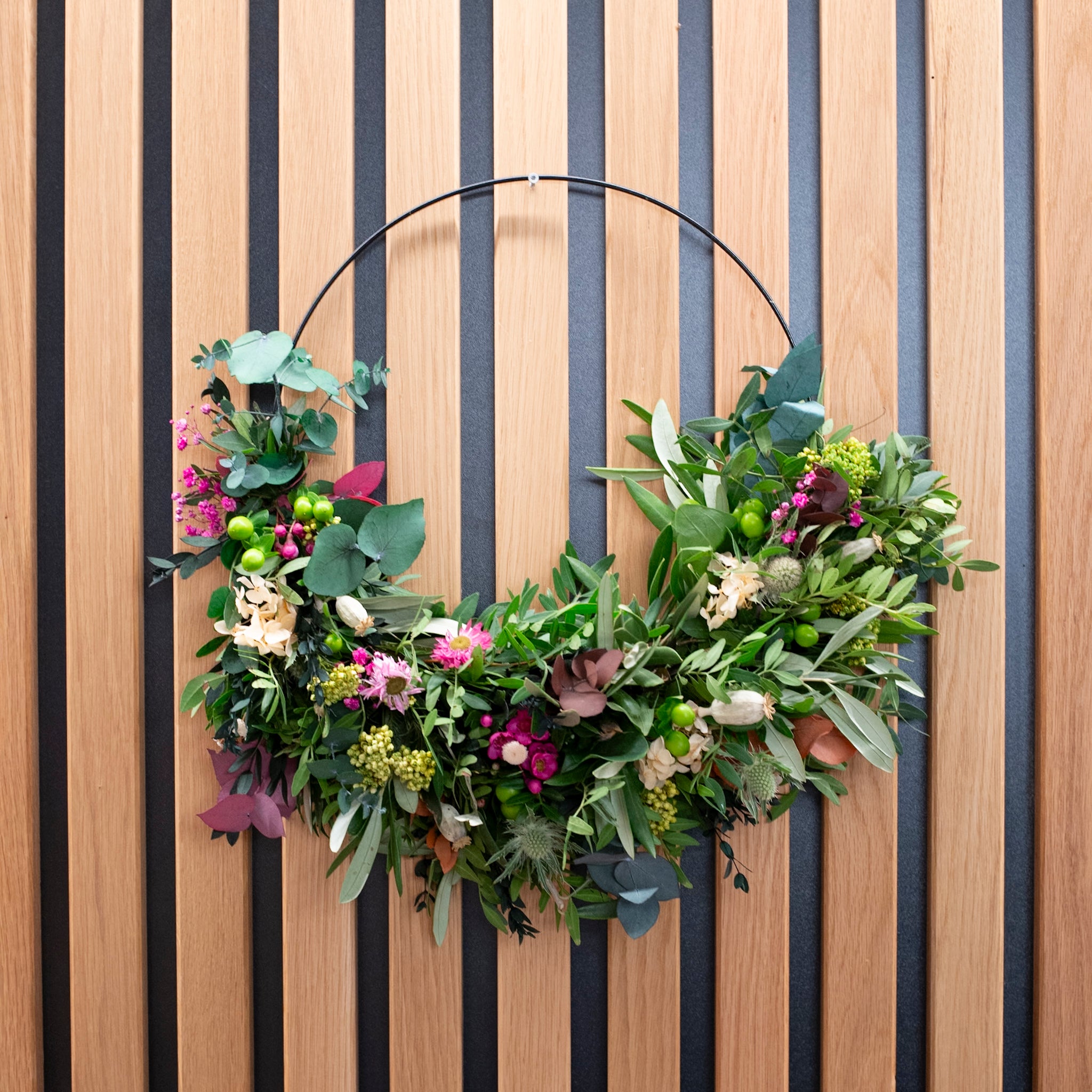 Minimalistischer Blumenkranz aus frischen Zweigen auf einem schwarzen Metallring von StraightCurls.