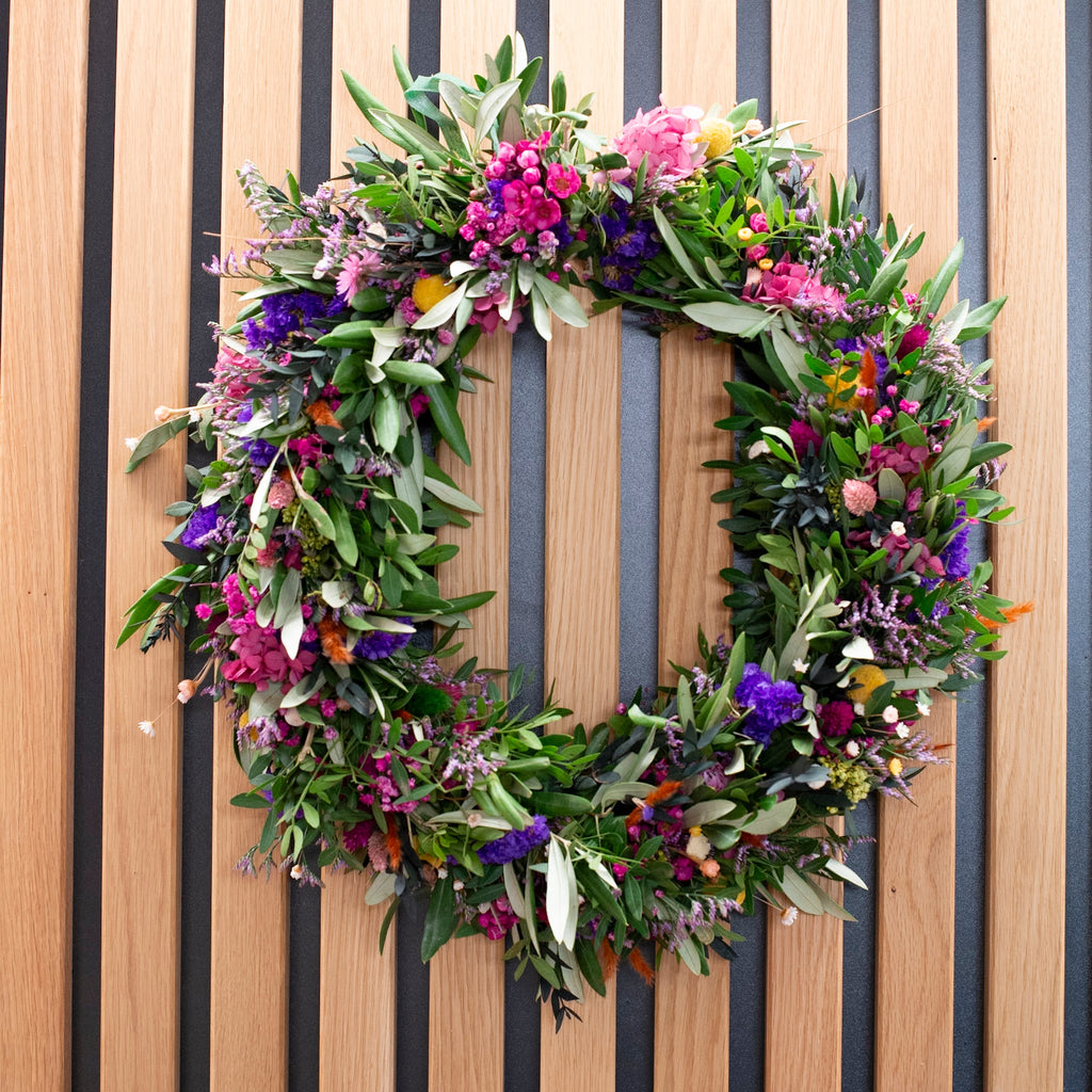 Klassischer runder Blumenkranz mit pinken Highlights und grünen Olivenzweigen von StraightCurls.