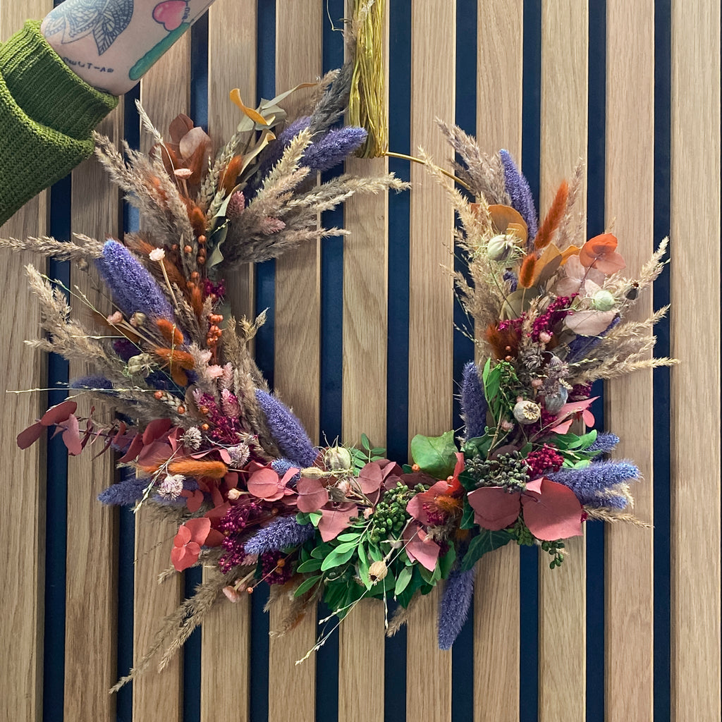 Voluminöser Kranz aus getrockneten Gräsern und lila Blütenelementen von StraightCurls.