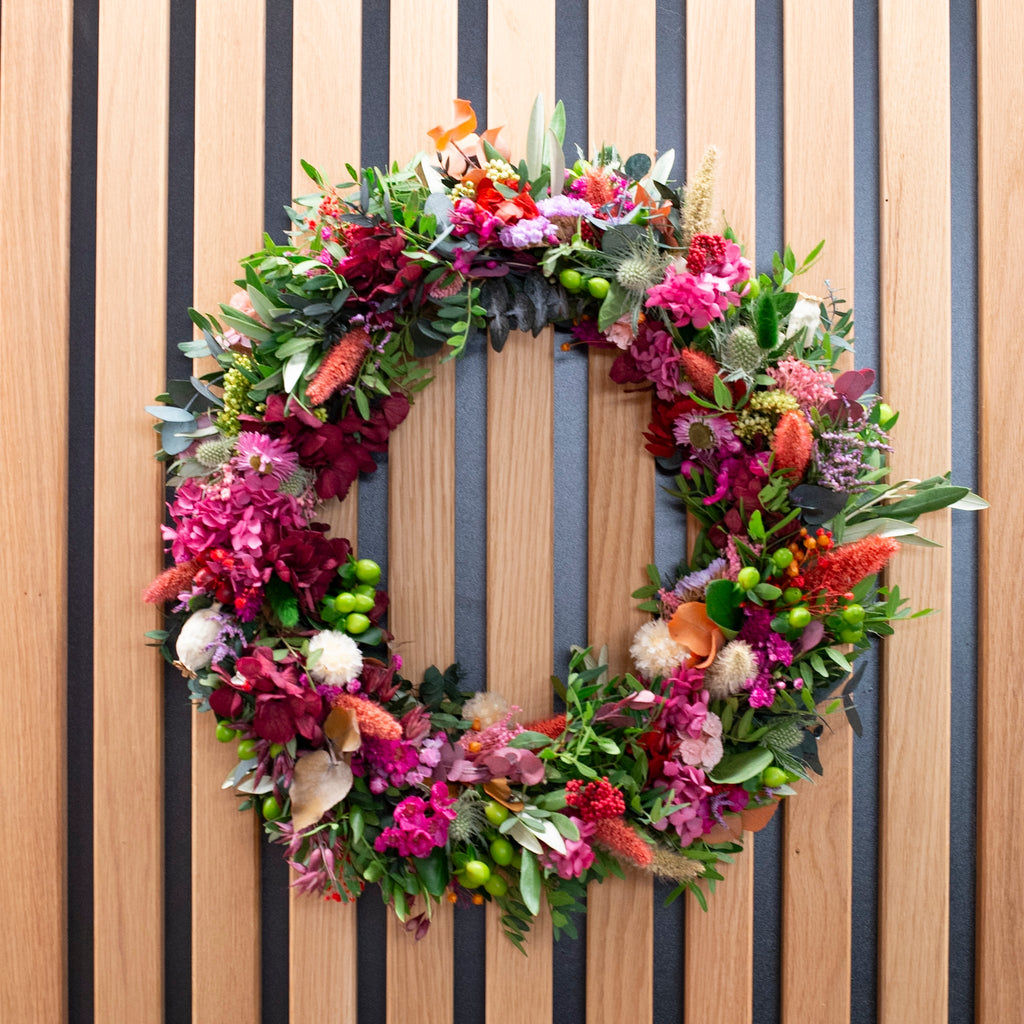 Ein besonders üppig und farbenfroh gestalteter Blumenkranz als exklusives Designobjekt von StraightCurls.