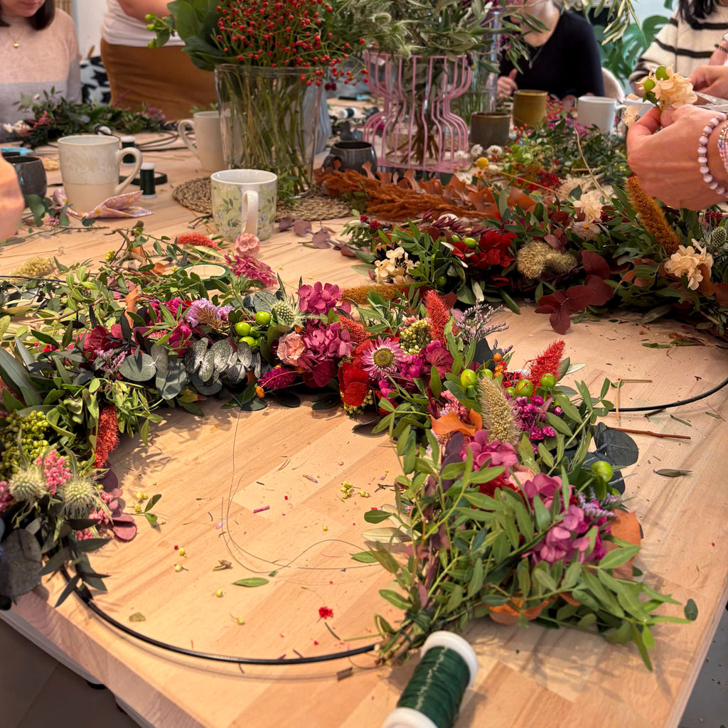 Blick auf den Workshoptisch während des Gestaltens floraler Kränze bei StraightCurls.