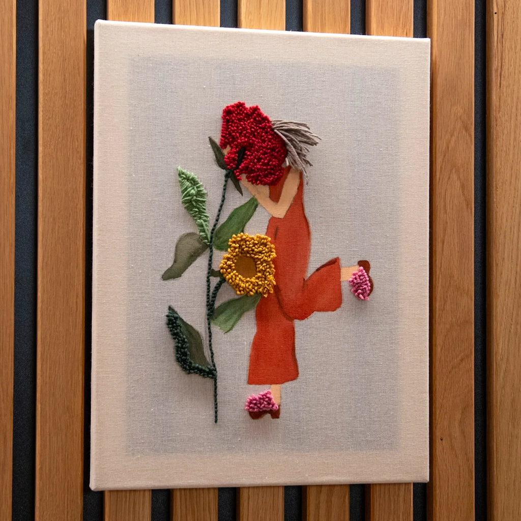Textilkunst einer Person in Orange mit roten und gelben Blumen, inspiriert von StraightCurls Punch Needle meets Acryl Workshop.