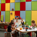 Fünf Personen basteln bei einem Punch Needle meets Acryl Workshop von StraightCurls im TIM Augsburg in einem farbenfrohen Raum.